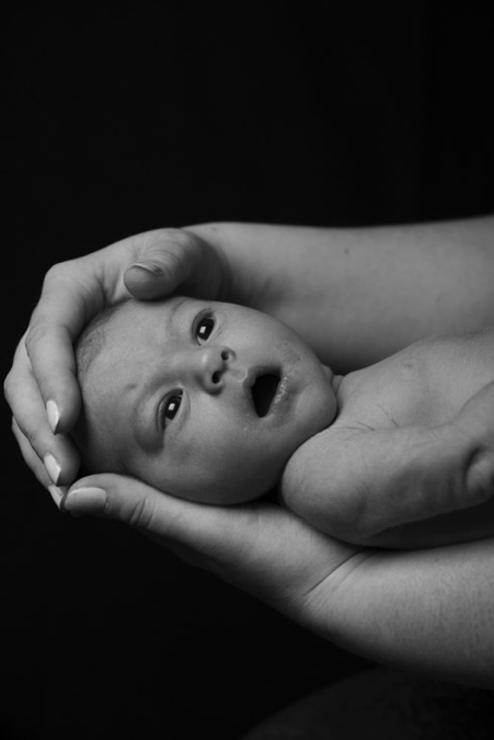 Photo en noir et blanc d'un nourrisson dans les mains de sa maman